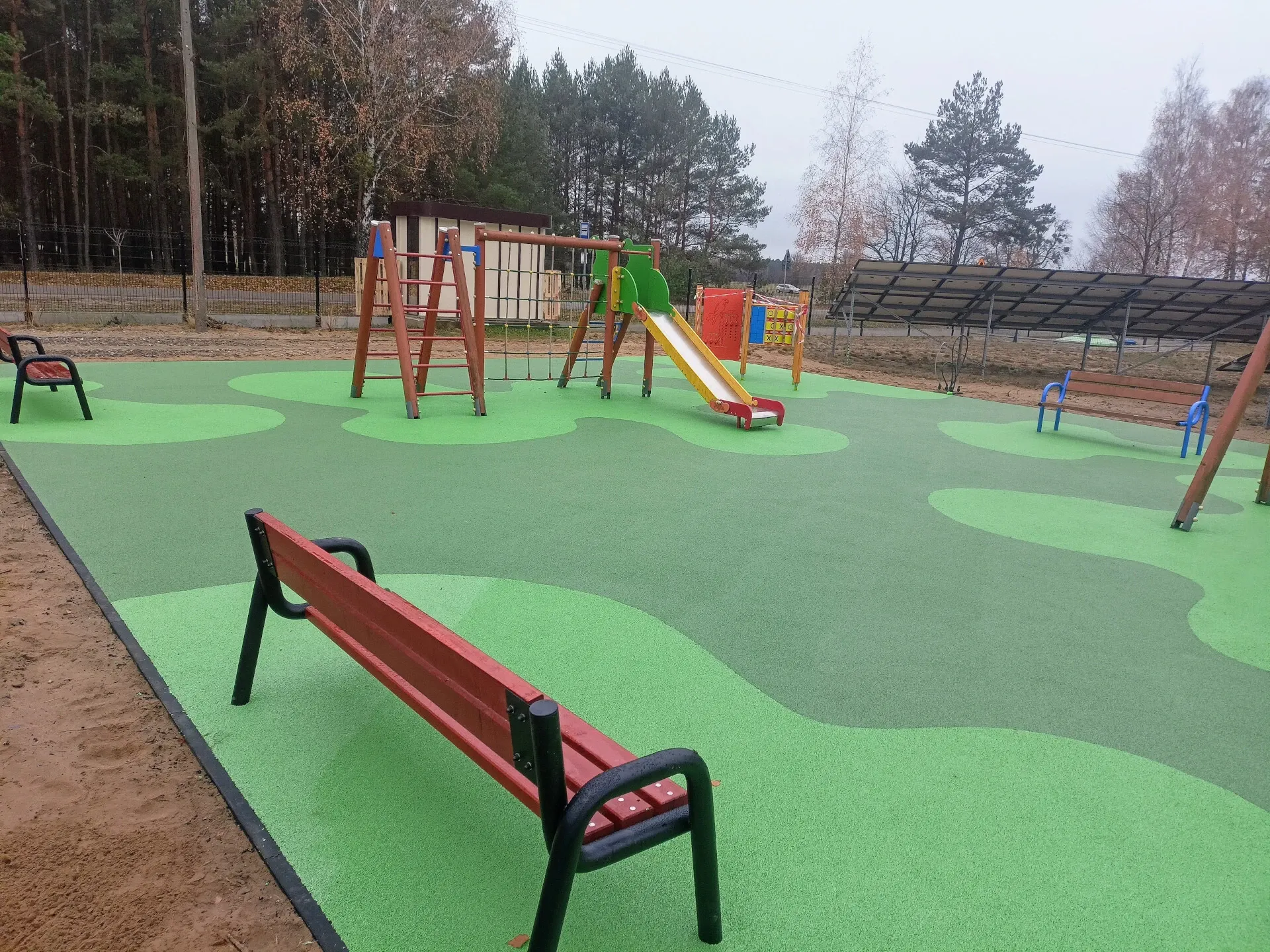 Plac zabaw z zieloną nawierzchnią bezpieczną i zestawami zabawowymi