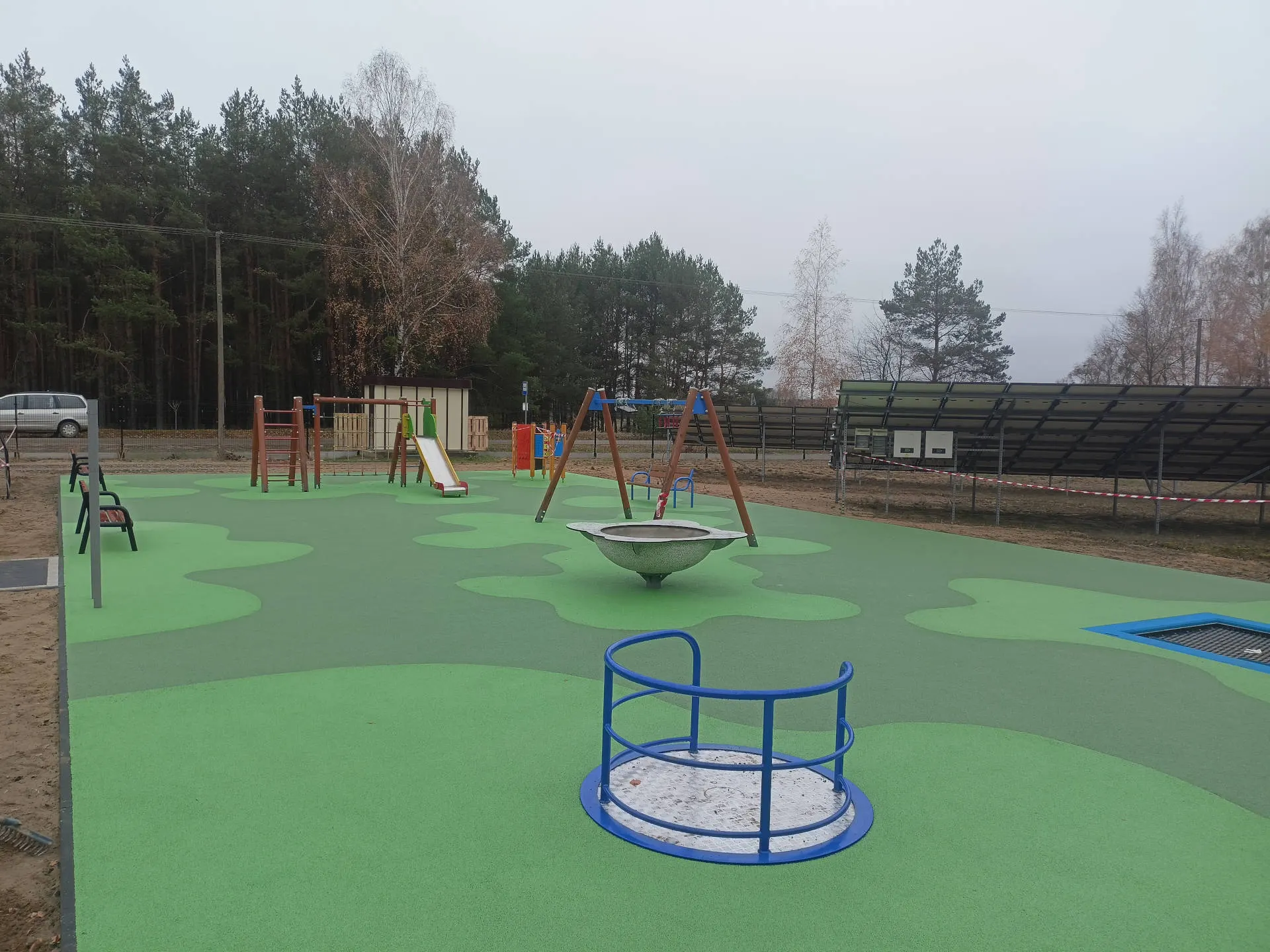 Rozległy plac zabaw z urządzeniami i zieloną nawierzchnią